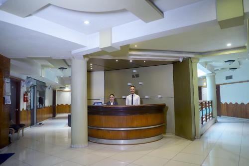 a man standing at a bar in a hospital lobby at Hotel Mansi in Vapi