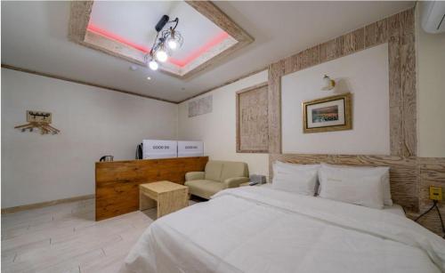 a bedroom with a white bed and a chair at Empire Motel in Cheonan