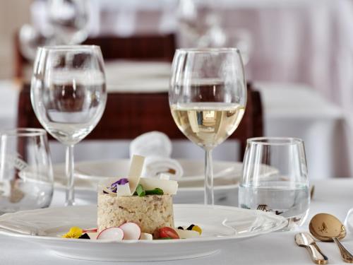a table with a plate of food and wine glasses at Pałac Potockich w Będlewie in Będlewo