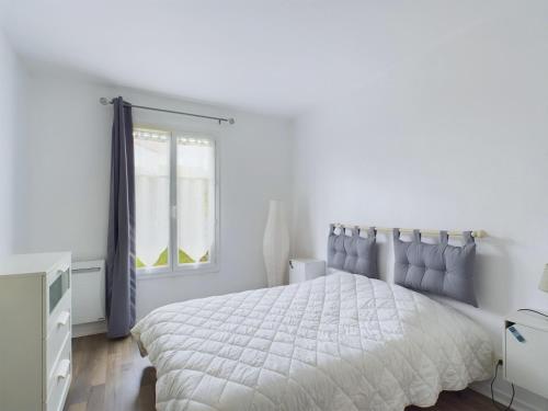 une chambre blanche avec un lit et une fenêtre dans l'établissement Les Sables d'Olonne - appartement pour 4 et jardin, à Les Sables-dʼOlonne
