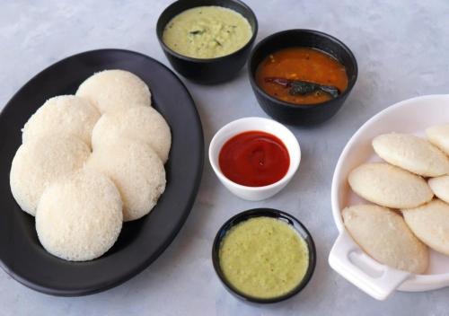 a table with a plate of food with biscuits and dipping sauces at Ocean View Beach Villa Varkala by VOYE HOMES in Varkala