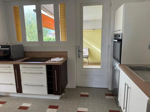 - une cuisine avec des placards blancs, un évier et une porte dans l'établissement Maison ancienne 163 avenue François Verdier albi, à Albi