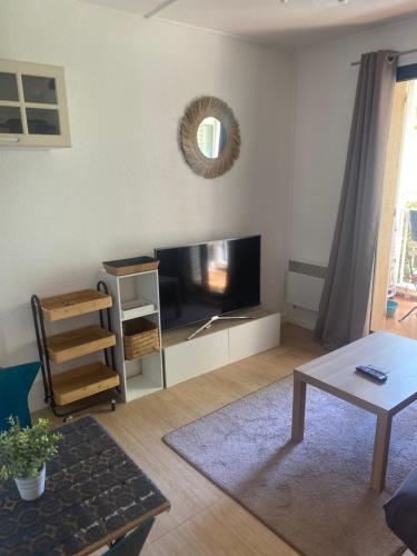 un salon avec une télévision à écran plat et une table dans l'établissement Sci des fontaines, à Six-Fours-les-Plages