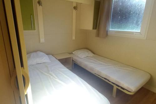 deux lits dans une petite pièce avec une fenêtre dans l'établissement le chalet de la source, à Saint-Sylvain