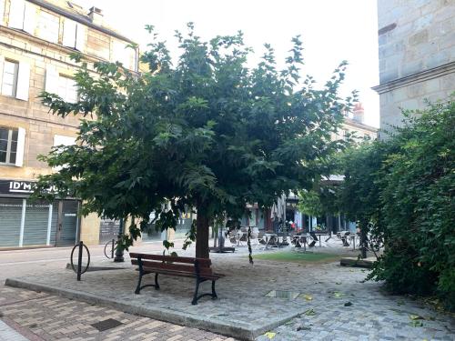a park bench under a tree in the middle of a street at appartement de charme centre historique de Brive in Brive-la-Gaillarde