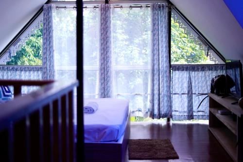 a bedroom with a bed and a large window at Lakeland Homestay Diphu in Diphu