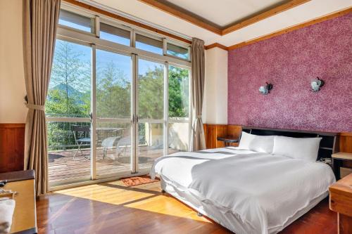 a bedroom with a large bed and a large window at Cingjing Star Lohas Manor B&B in Renai
