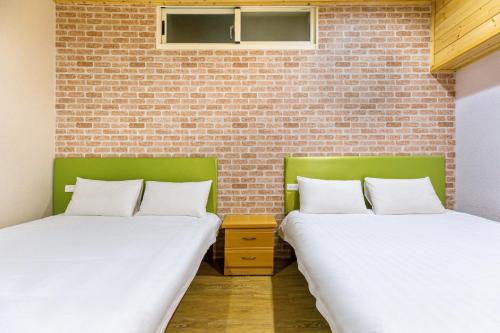 two beds in a room with a brick wall at Cingjing Star Lohas Manor B&B in Renai