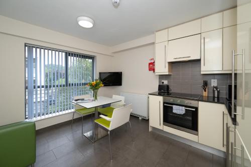 a kitchen with white cabinets and a table with chairs at Victoria Lodge - UCC Summer Beds in Cork
