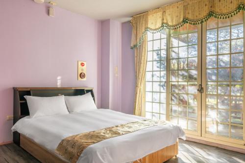 a bedroom with a bed and a large window at Cingjing Star Lohas Manor B&B in Renai
