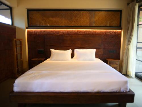 a bedroom with a large bed with a wooden headboard at Villa Katipadu Coorg in Srimangala