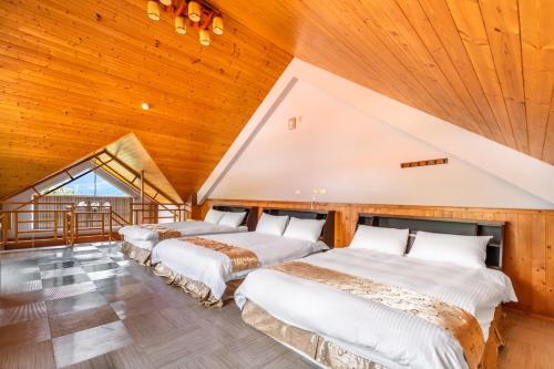 three beds in a room with a wooden ceiling at Cingjing Star Lohas Manor B&B in Renai
