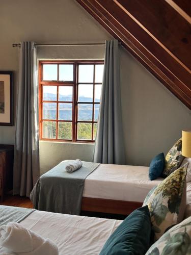 Un dormitorio con dos camas y una ventana. en Drakensberg Mountain Retreat, en Bergville