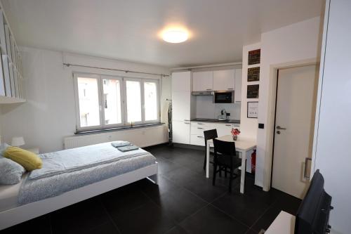 Un dormitorio con una cama y una mesa y una cocina. en Apartment near train station, en Luxemburgo