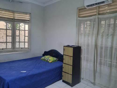 a bedroom with a blue bed and two windows at Homes stay Lily in Semplak