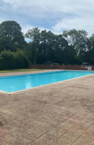 a blue swimming pool with trees in the background at Lakeside Lodge 84 in Caeathro