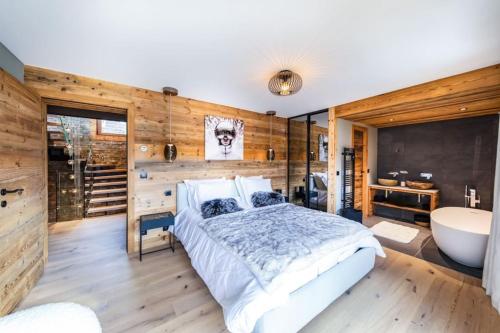 a bedroom with a large bed and a bath tub at Exceptionnel Chalet Design - 12 pers - Ski au pied in Les Gets