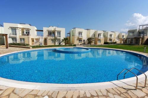 ein großer Pool vor einigen Apartmentgebäuden in der Unterkunft Mountain Seaview Penthouse in a Holiday Village 10 in Ayios Yeoryios