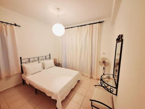 ein Schlafzimmer mit einem weißen Bett und einem Fenster in der Unterkunft Mountain Seaview Penthouse in a Holiday Village 10 in Ayios Yeoryios