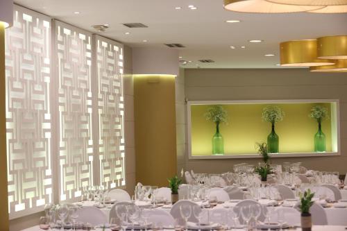 a banquet hall with white tables and green vases at Hotel Alfonso IX in Sarria