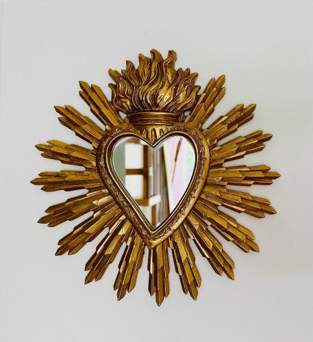 a gold sunburst mirror with a heart on a wall at Le Roquefeuil T4 Duplex St-Gilles in Saint-Paul