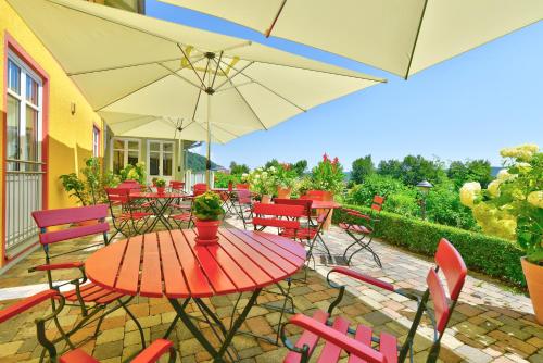 a patio with a red table and chairs with umbrellas at Hotel Auf Wolke 8 in Trostberg an der Alz