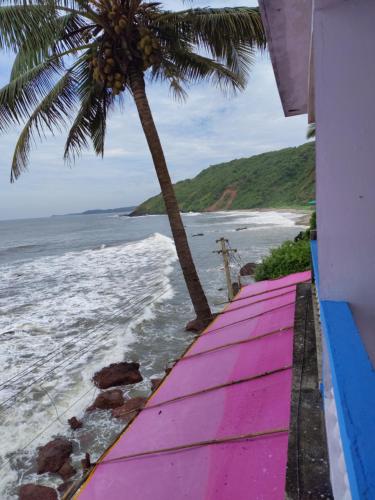a view of a beach with a palm tree and the ocean at Shree Sai Beach Stay in Arambol