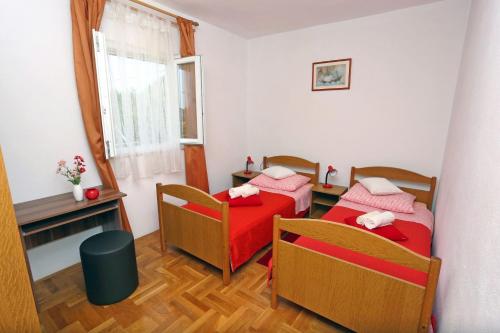 ein Zimmer mit zwei Betten und einem Tisch und einem Fenster in der Unterkunft Apartment Marija in Drvenik Mali
