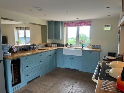 a large kitchen with blue cabinets and a window at Tranquil 4-bed Spectacular Views in Much Birch