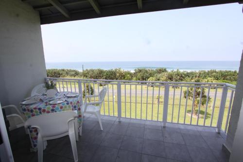 a balcony with a table and chairs and the ocean at Jakaranda 22 apartment, Uvongo in Uvongo Beach