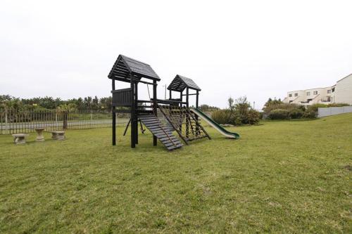 a playground with a slide in the grass at Jakaranda 22 apartment, Uvongo in Uvongo Beach