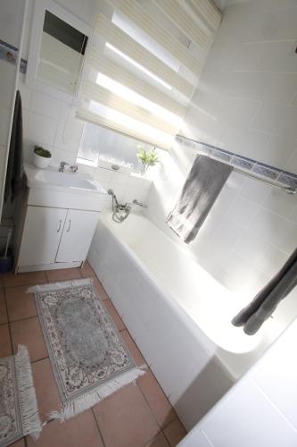 a white bathroom with a tub and a sink at Jakaranda 22 apartment, Uvongo in Uvongo Beach
