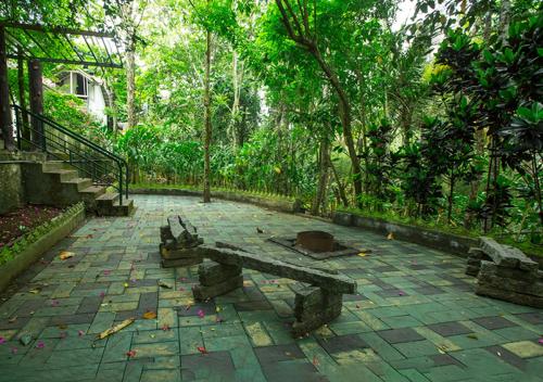 Un banco de piedra sentado en un patio de un parque. en Spezia Private Plantation Bungalow Thekkady by VOYE HOMES, en Thekkady