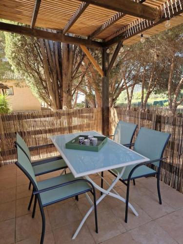 une table et des chaises sur une terrasse sous une pergola dans l'établissement Mini villa 70 - piscine chauffée, à Serra-di-Ferro