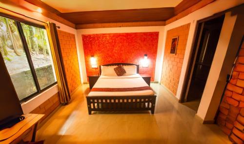 Una pequeña habitación con una cama y un televisor. en Spezia Private Plantation Bungalow Thekkady by VOYE HOMES, en Thekkady