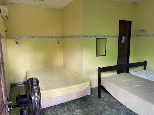two beds in a room with yellow walls at Chácara Arco Íris in Conde