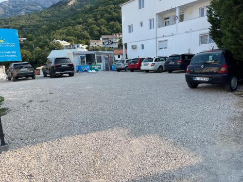 a parking lot with cars parked in front of a building at Relax Apartmani in Sutomore