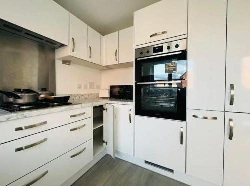 a white kitchen with white cabinets and appliances at Ashford Luxury House with Hot tub and Driveway Parking in Kingsnorth