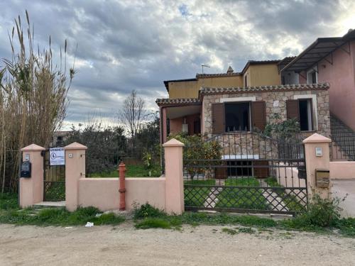 a house with a fence and a fire hydrant at Villa Samuele - Porto Frailis in Àrbatax