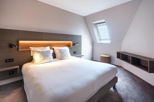 a bedroom with a large white bed with a window at Hotel L'Europe in Colmar