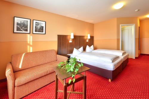 een hotelkamer met een bed en een bank bij Hotel Auf Wolke 8 in Trostberg an der Alz