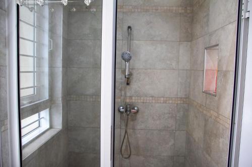 a bathroom with a shower with a glass door at Family 3bed House in Kampala