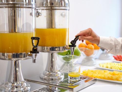 a person pouring orange juice into a blender at Hotel Rey Alfonso X in Seville
