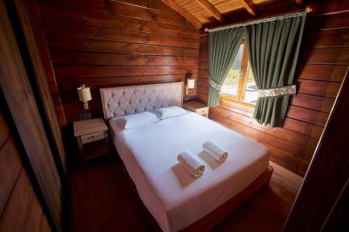 a bedroom with a bed with two towels on it at Flora Handüzü Resort & Wellness Bungalow Hotel in Rize