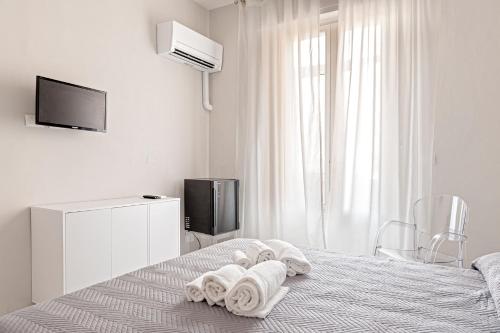 a white bedroom with towels on a bed at The Port Residence in Livorno