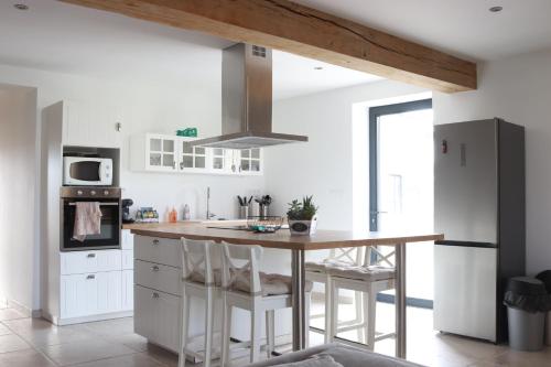 a kitchen with white cabinets and a wooden island with stools at Maison medocaine familiale in Saint-Sauveur