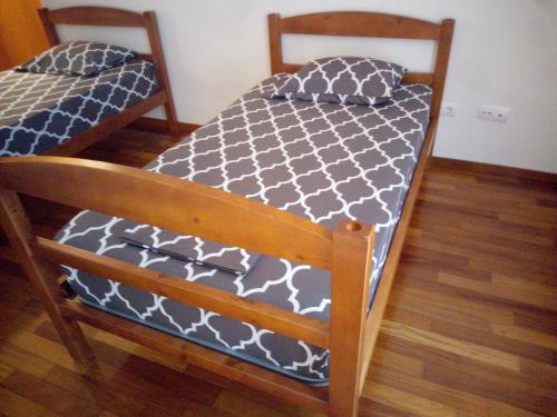 two twin beds in a room with wood floors at Costa Lodges, Funchal or Santa Cruz Madeira, shared room in Santa Cruz