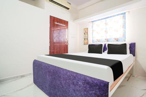a bedroom with a large bed with purple accents at Hotel O CROWN in Nagpur
