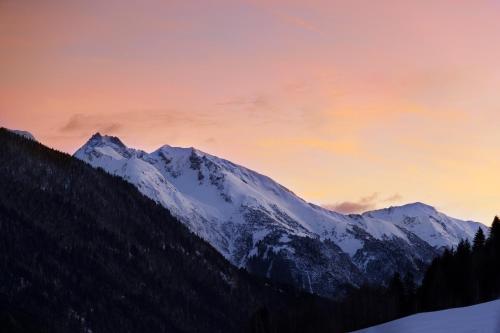 a snow covered mountain with a sunset in the background at Valluga Hotel in Sankt Anton am Arlberg
