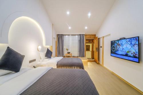 a hotel room with two beds and a flat screen tv at Leisure Inn in Lijiang